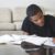 Stock image of a teenage boy doing homework at a living room table