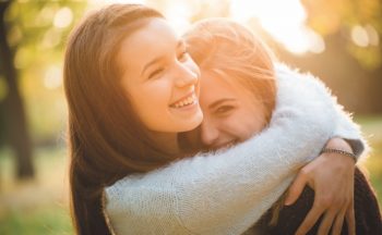 Stock image of two girls hugging and laughing together outdoors