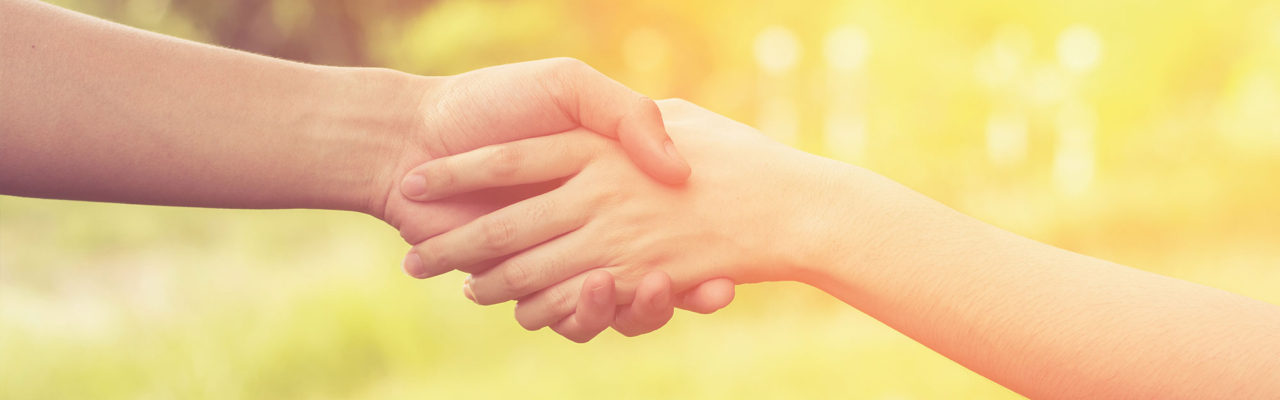 Stock image framed in close up of two peoples hands, one lifting the other upwards